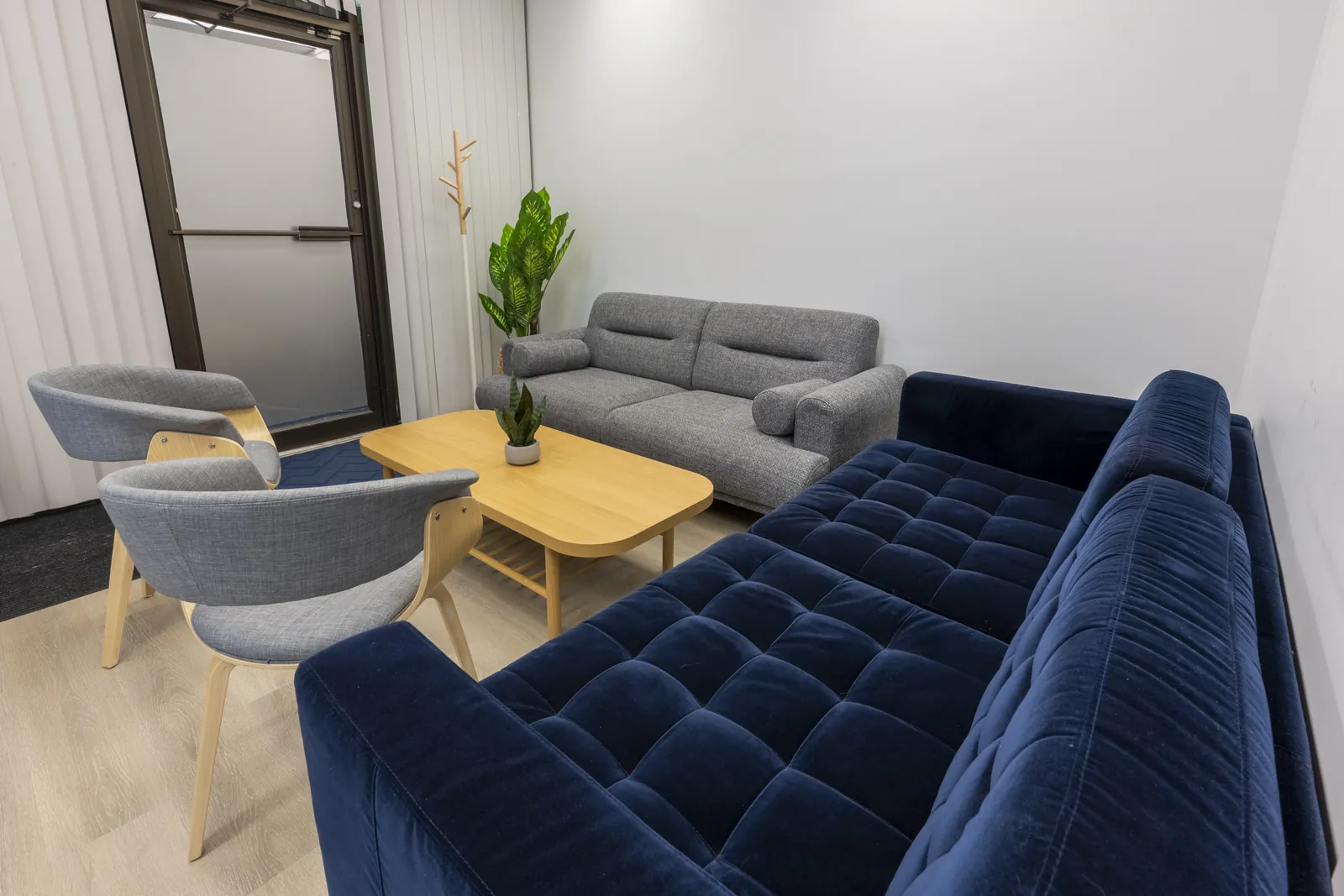 Therapy room at the Toronto Family Therapy office on Merton Street, with a navy velvet sofa, a grey sofa and two armchairs