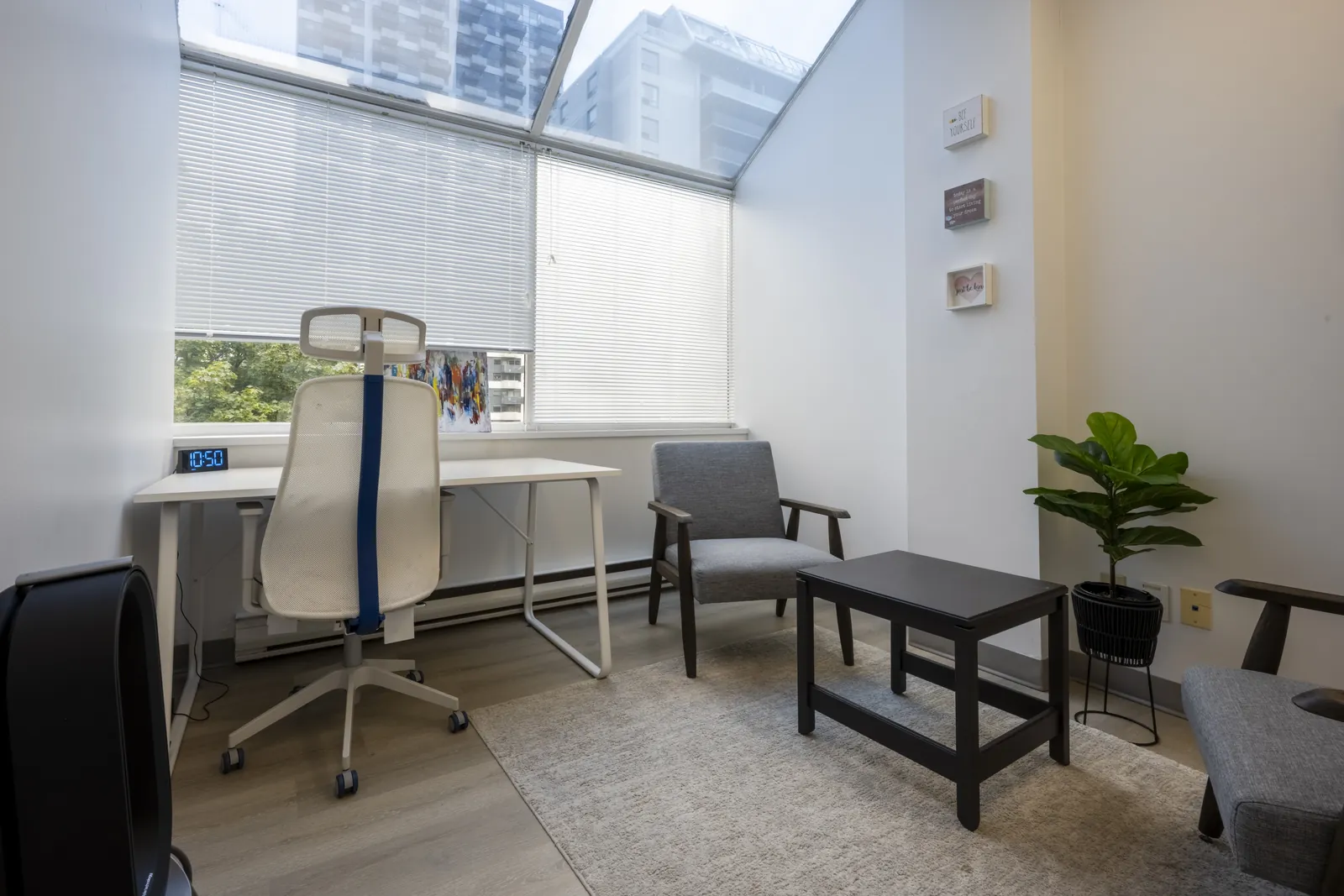 Therapy room at the Merton Street office with a slanted glass window looking out on midtown towers