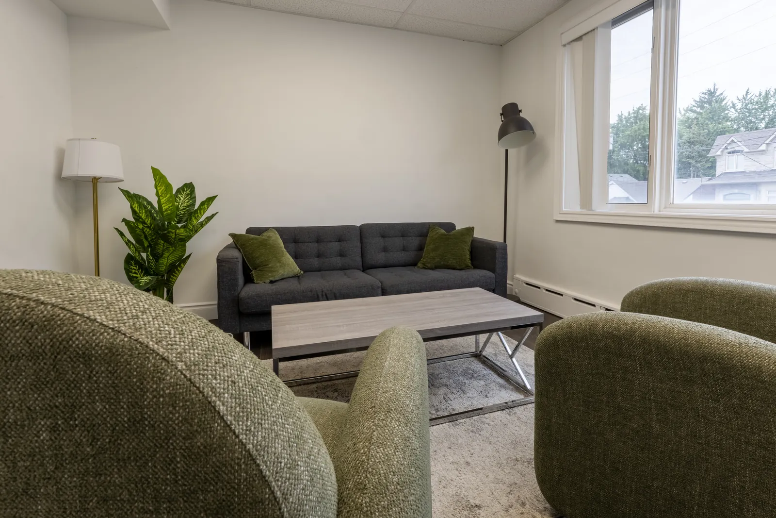 Therapy room at the Toronto Family Therapy North York office, with green armchairs and a grey sofa